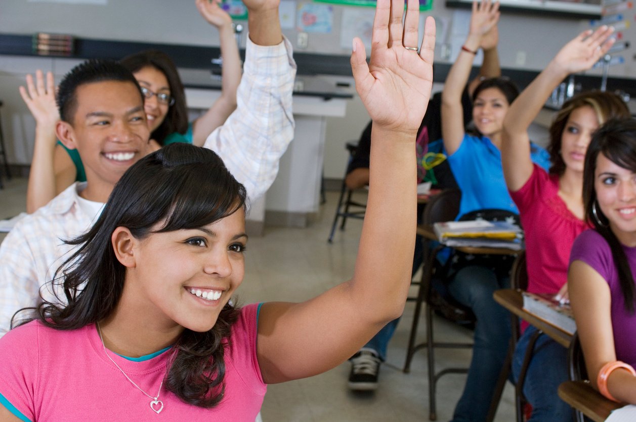 High school students raising their hands in class